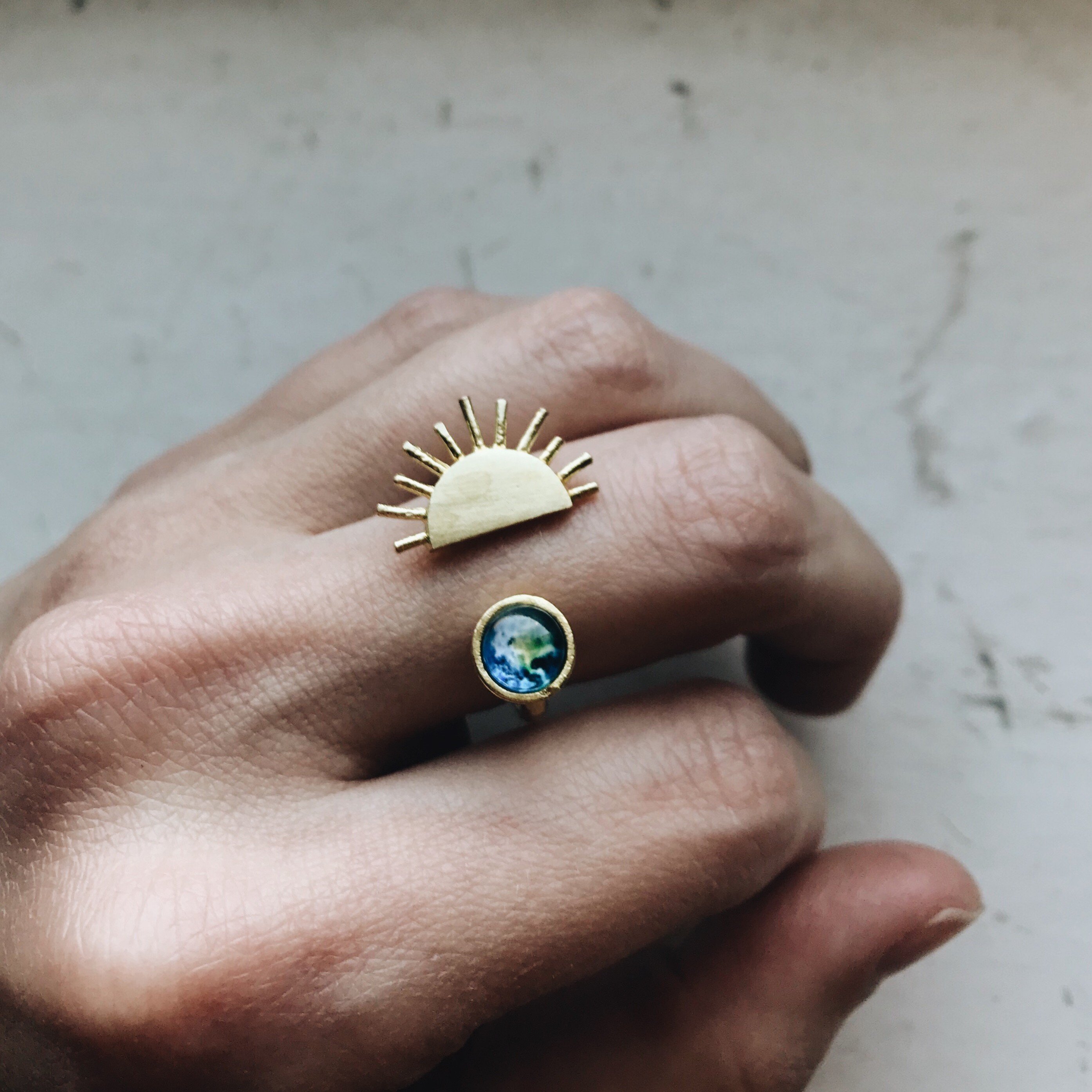 A stunning Sunrise Ring featuring a sun design on an adjustable hammered band in silver or gold tone, symbolizing beauty and elegance.