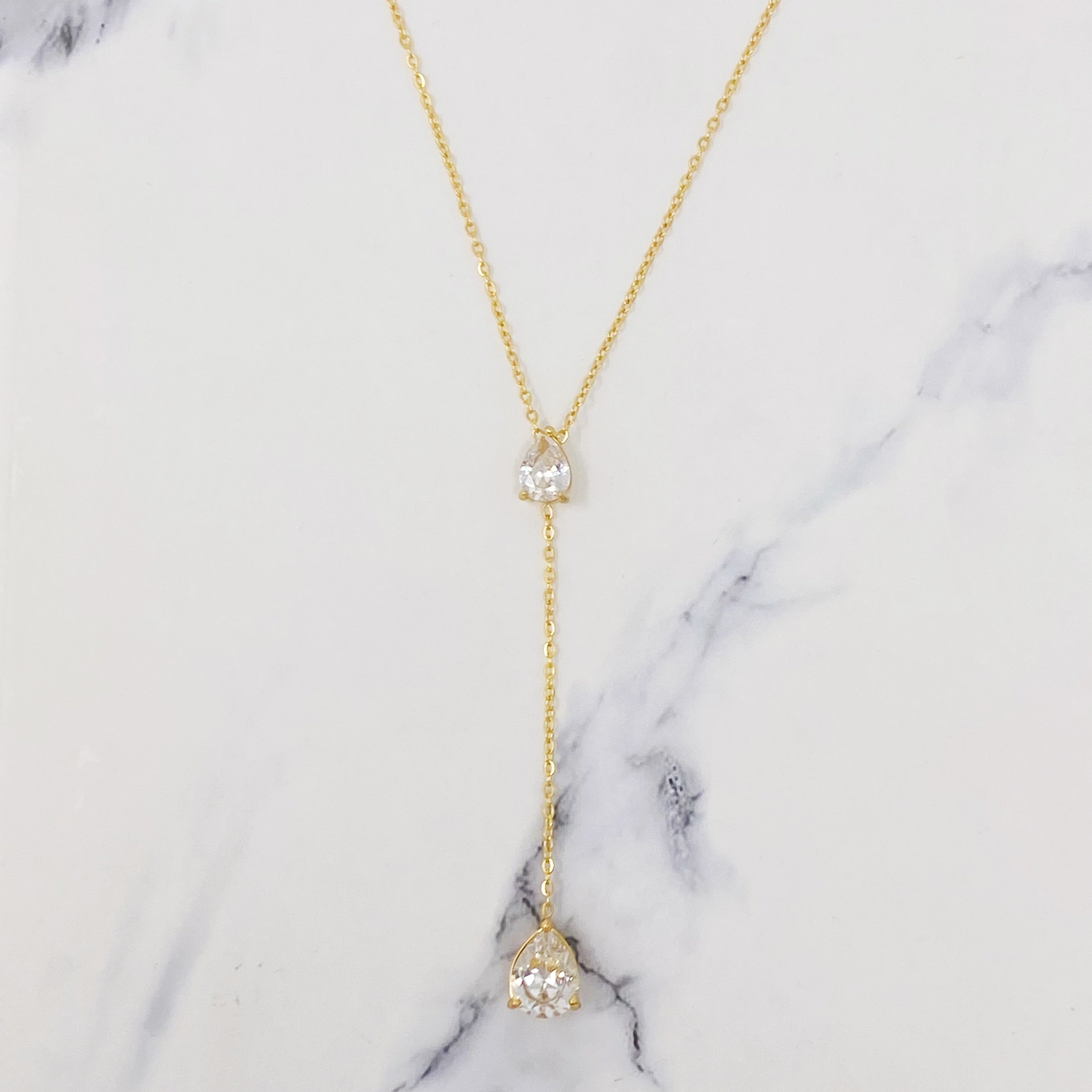 A beautiful Superior Shine Drop Necklace featuring two tear drop Cubic Zirconia stones on a dainty 18k gold plated stainless steel chain.