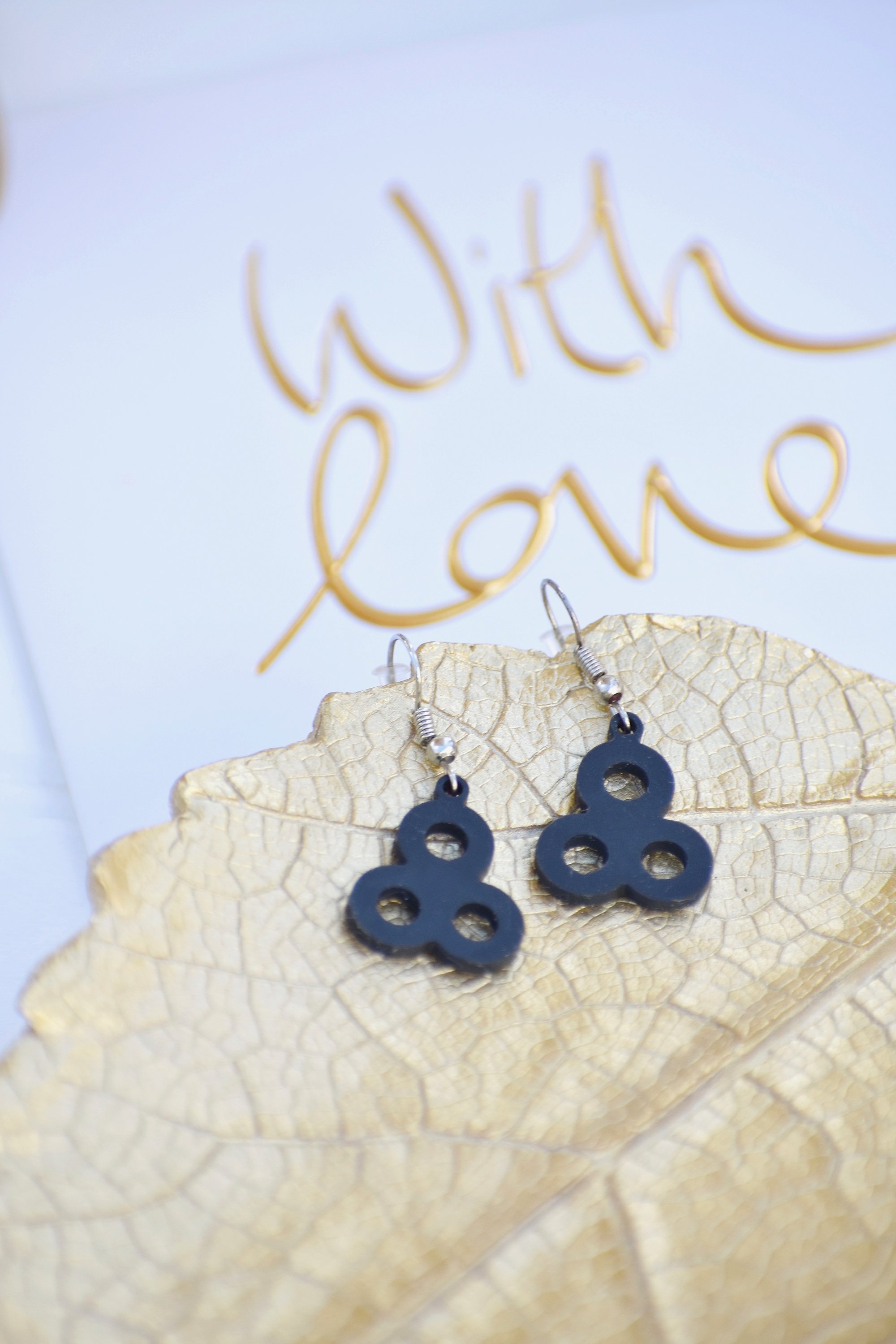 A pair of elegant Sweet Earrings displayed in a velvet pouch, showcasing their unique design and lightweight features.