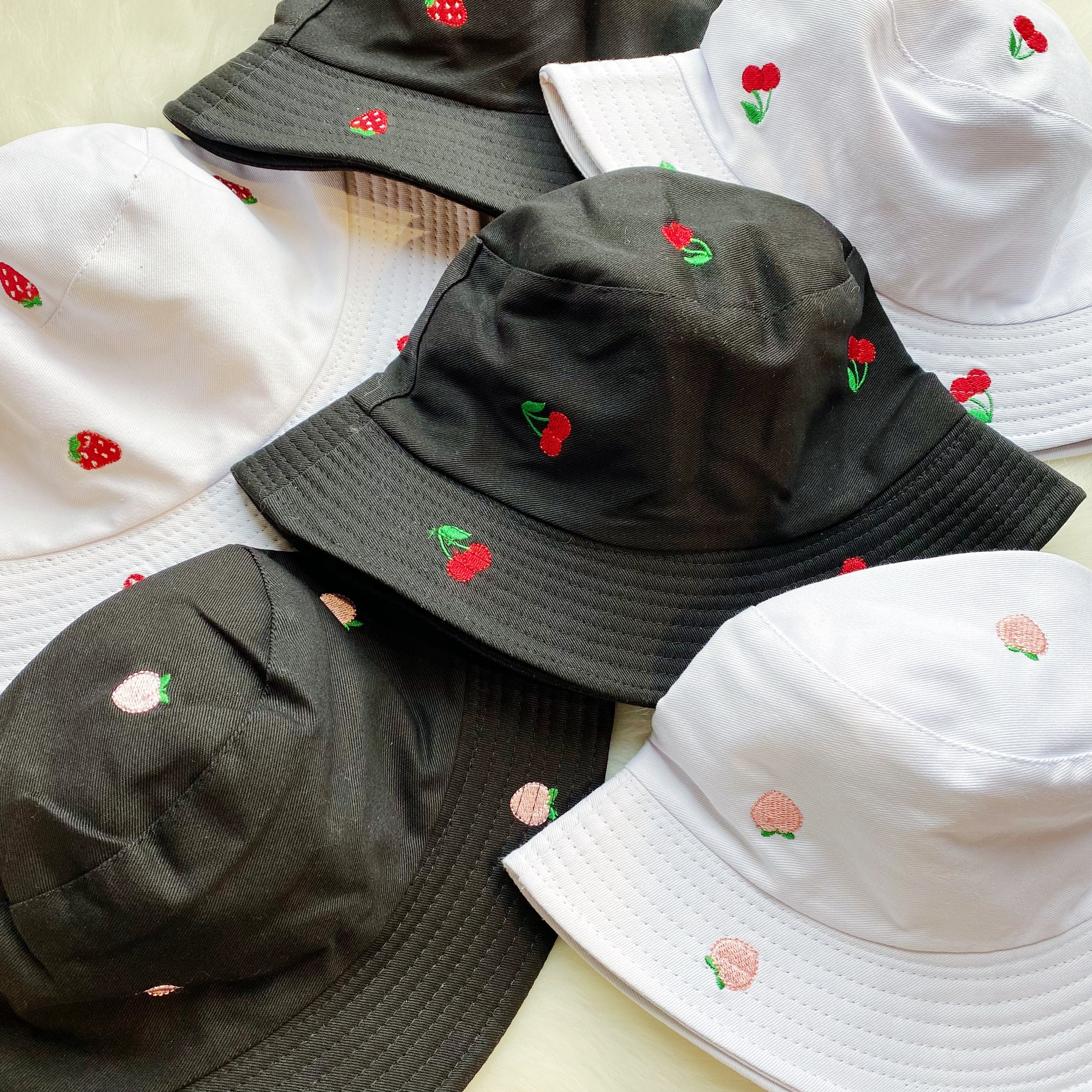 A stylish Sweety Fruity Bucket Hat featuring colorful embroidered fruit patterns on a high-quality cotton fabric, perfect for summer wear.