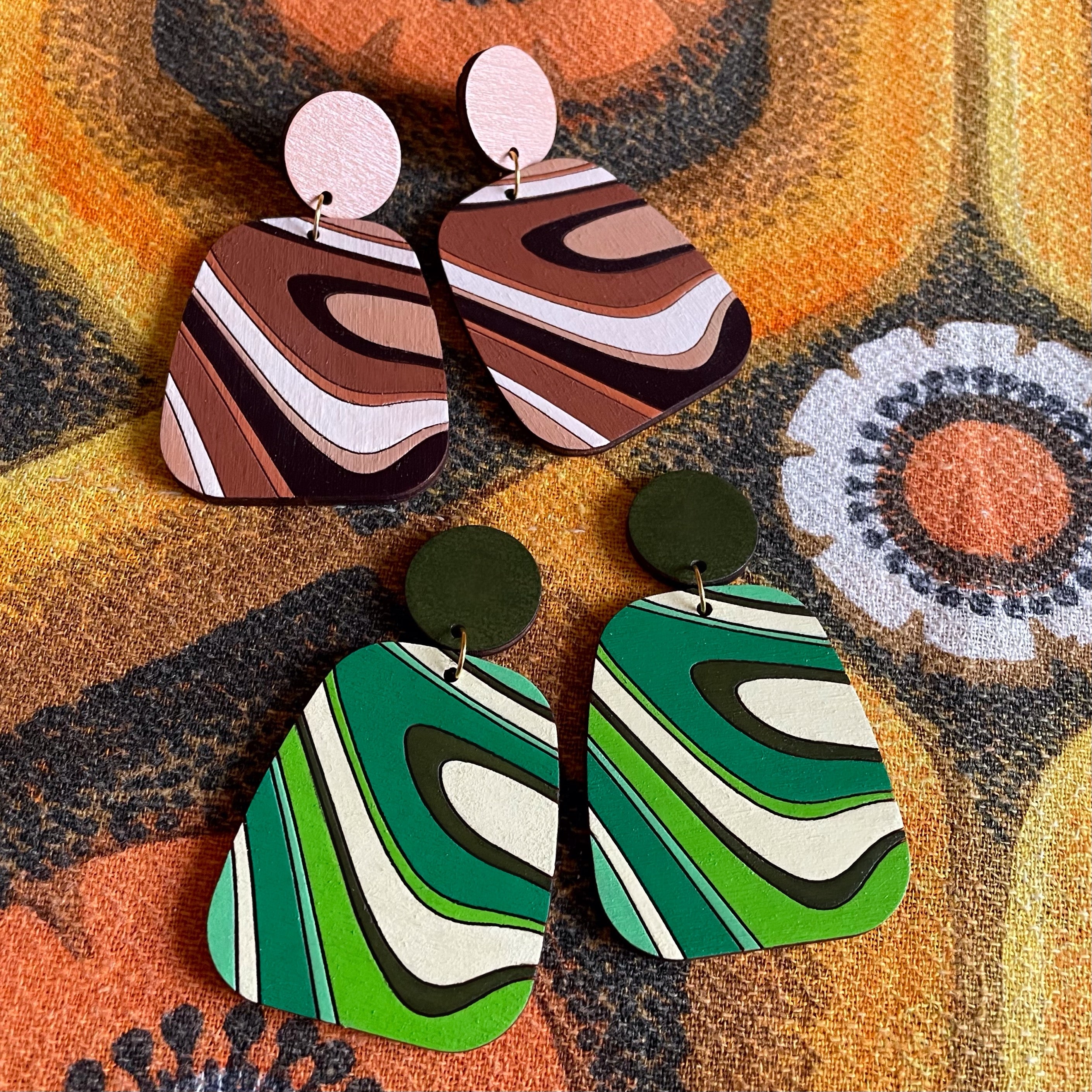 A pair of handcrafted Swirl Wood Earrings featuring intricate laser-cut designs, painted in vibrant colors, showcasing natural wood grain.