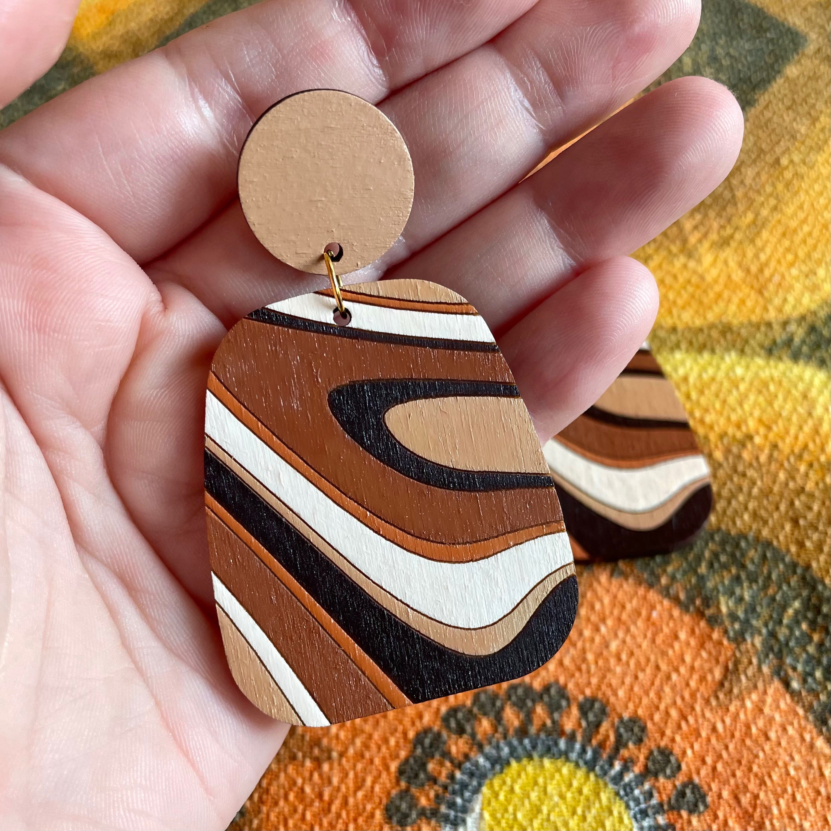 A pair of handcrafted Swirl Wood Earrings featuring intricate laser-cut designs, painted in vibrant colors, showcasing natural wood grain.