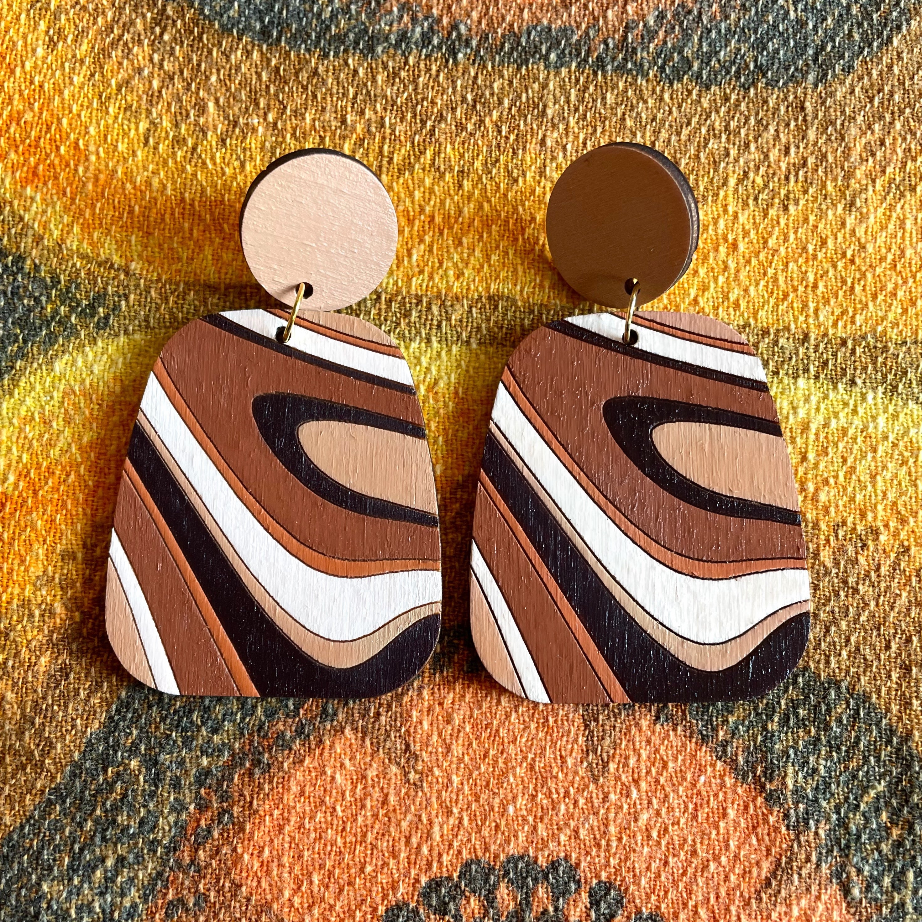 A pair of handcrafted Swirl Wood Earrings featuring intricate laser-cut designs, painted in vibrant colors, showcasing natural wood grain.