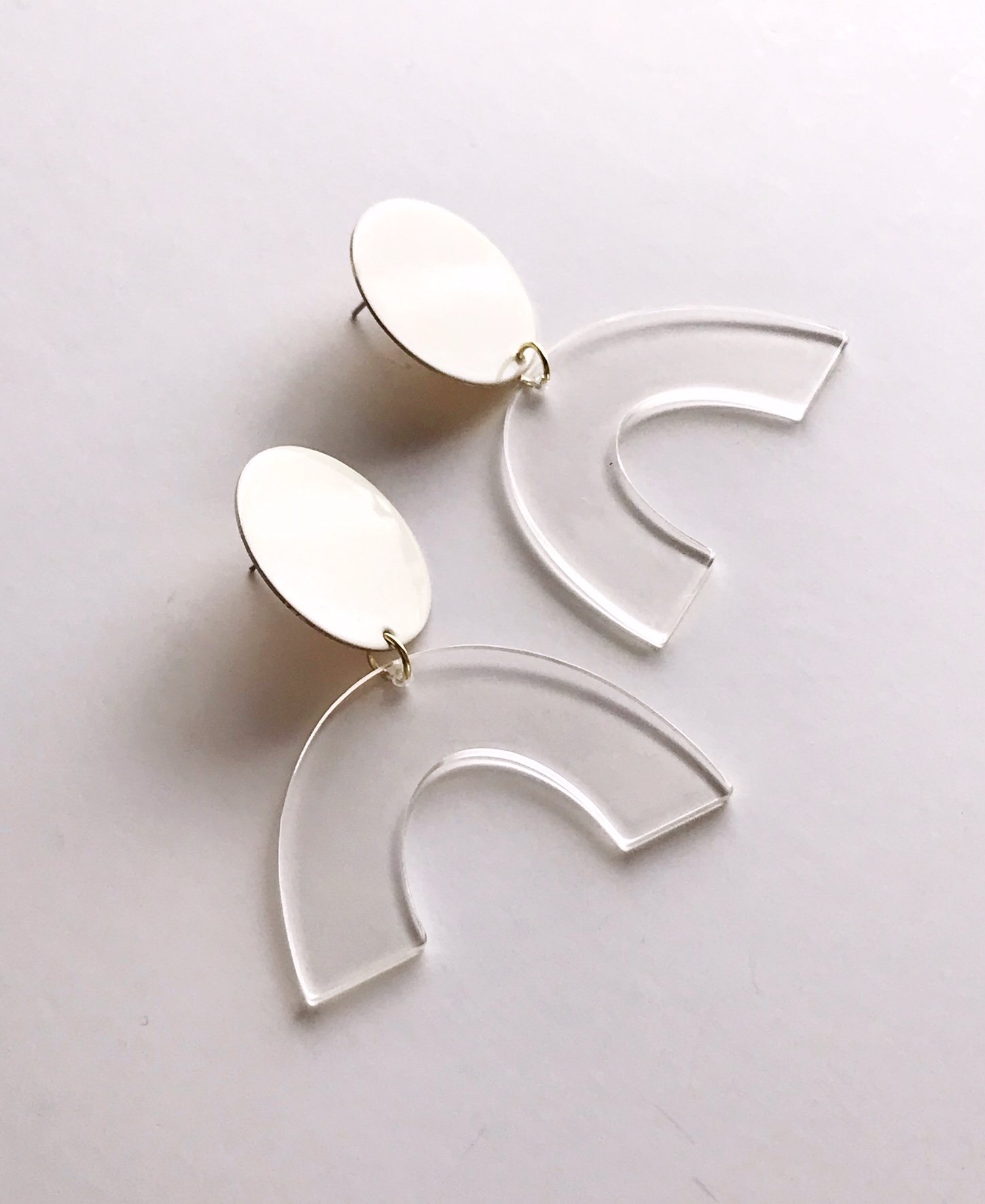 Sydney earrings featuring ivory painted brass discs and clear faux tortoise shell arches, lightweight and stylish.