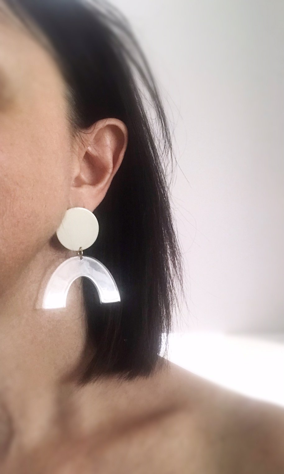 Sydney earrings featuring ivory painted brass discs and clear faux tortoise shell arches, lightweight and stylish.