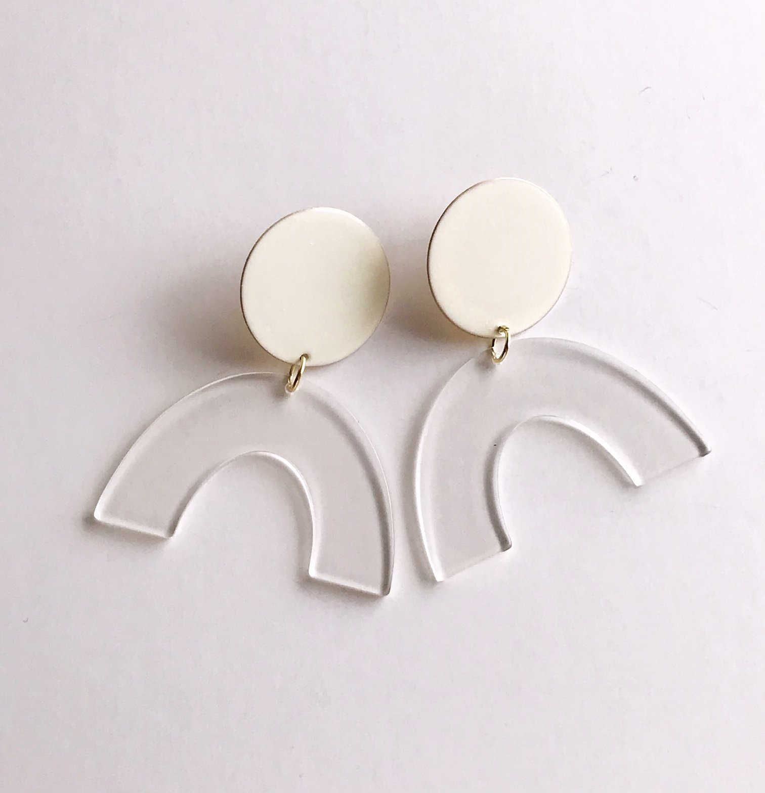 Sydney earrings featuring ivory painted brass discs and clear faux tortoise shell arches, lightweight and stylish.