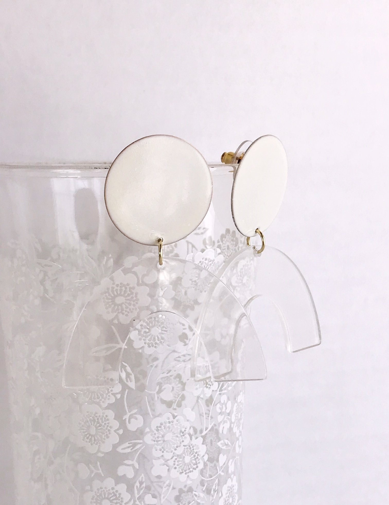 Sydney earrings featuring ivory painted brass discs and clear faux tortoise shell arches, lightweight and stylish.