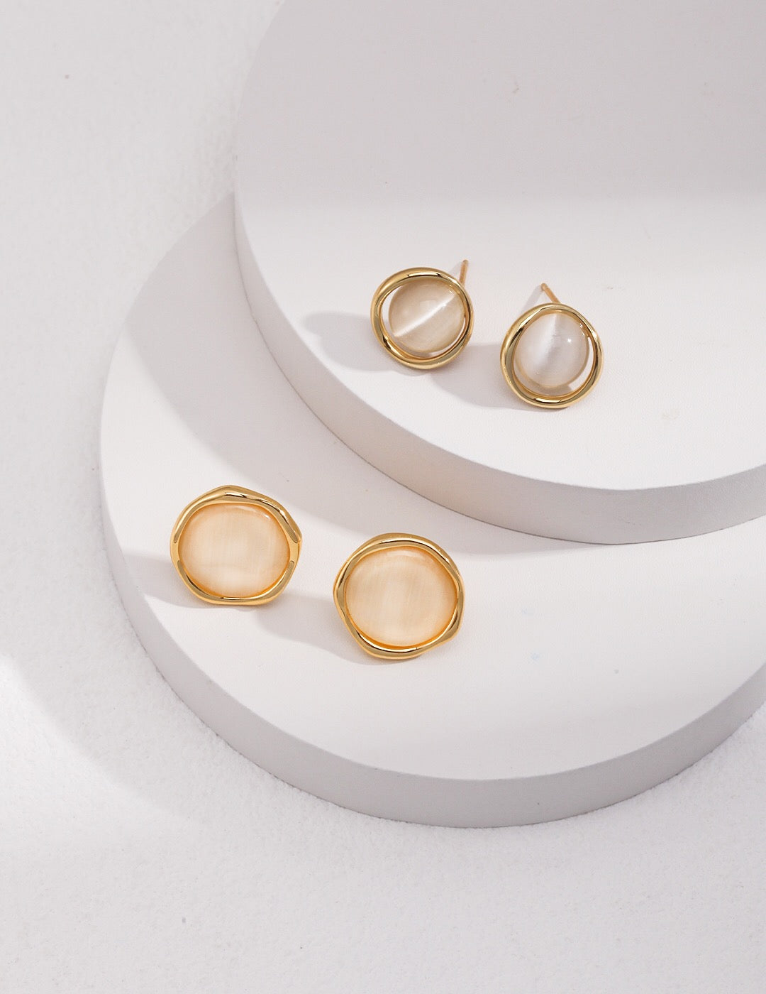 A pair of elegant synthetic cat's eye stud earrings, featuring a gold vermeil finish on sterling silver, showcasing their unique glow.