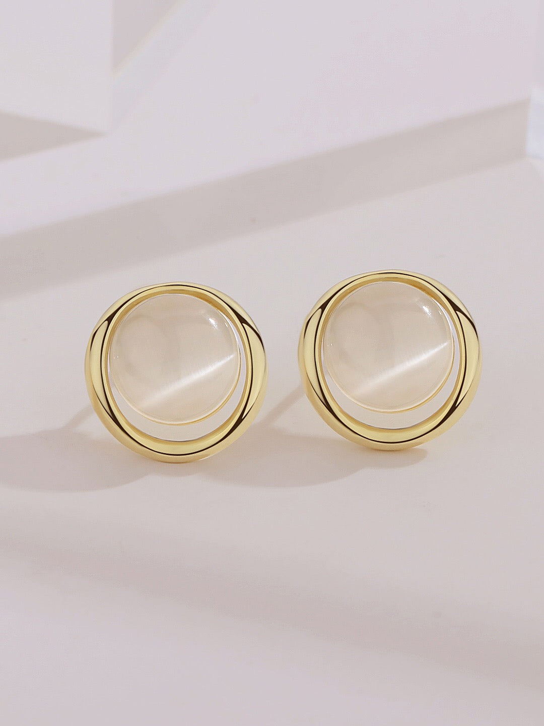 A pair of elegant synthetic cat's eye stud earrings, featuring a gold vermeil finish on sterling silver, showcasing their unique glow.