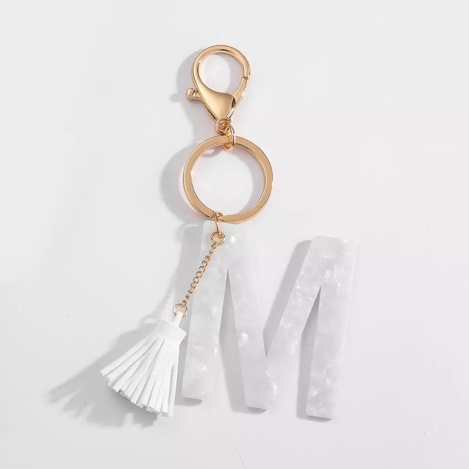 Stylish white key chain featuring a tassel and personalized initial, perfect for organizing keys.