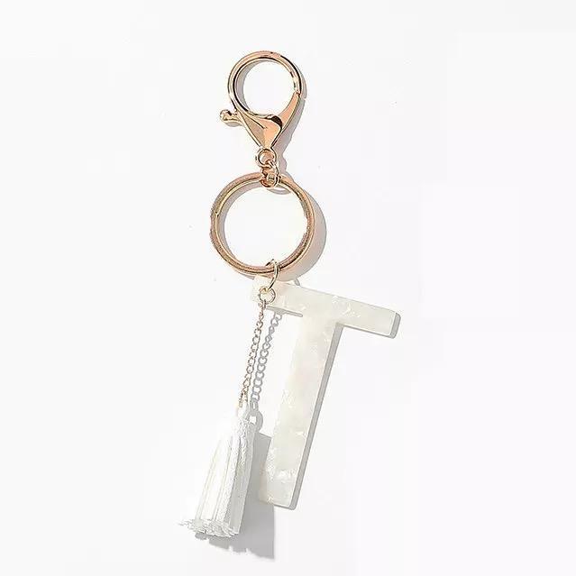 Stylish white key chain featuring a tassel and personalized initial, perfect for organizing keys.