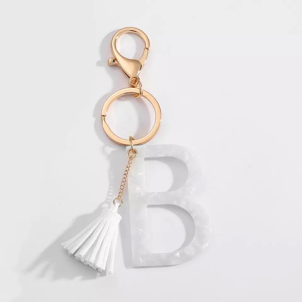 Stylish white key chain featuring a tassel and personalized initial, perfect for organizing keys.