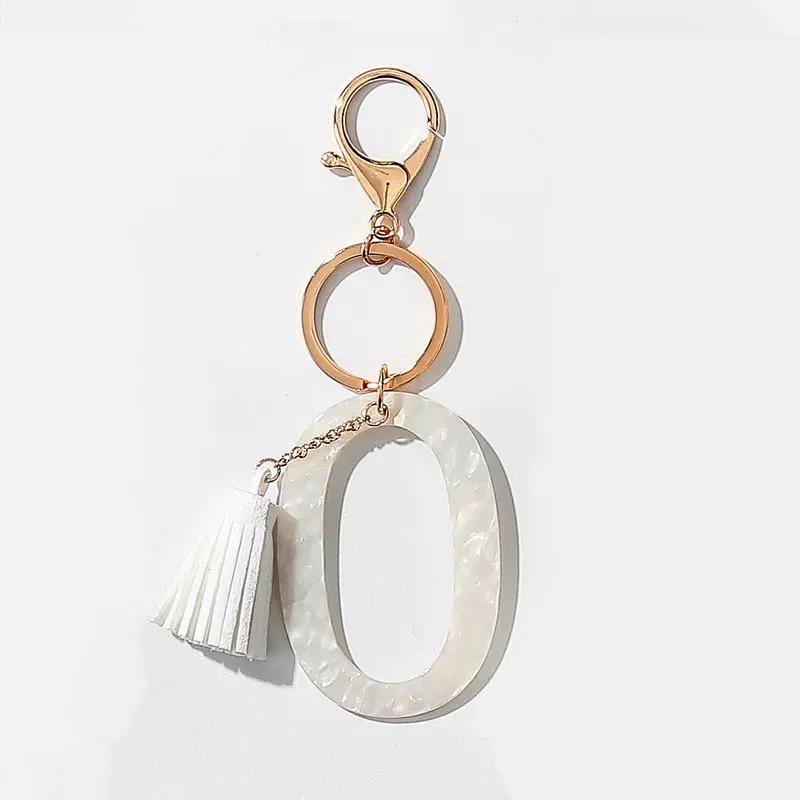 Stylish white key chain featuring a tassel and personalized initial, perfect for organizing keys.