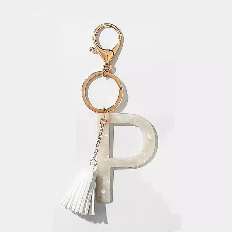 Stylish white key chain featuring a tassel and personalized initial, perfect for organizing keys.