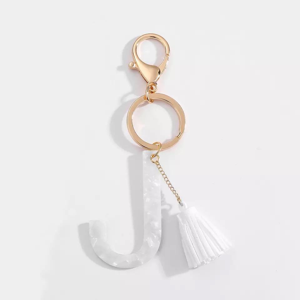 Stylish white key chain featuring a tassel and personalized initial, perfect for organizing keys.