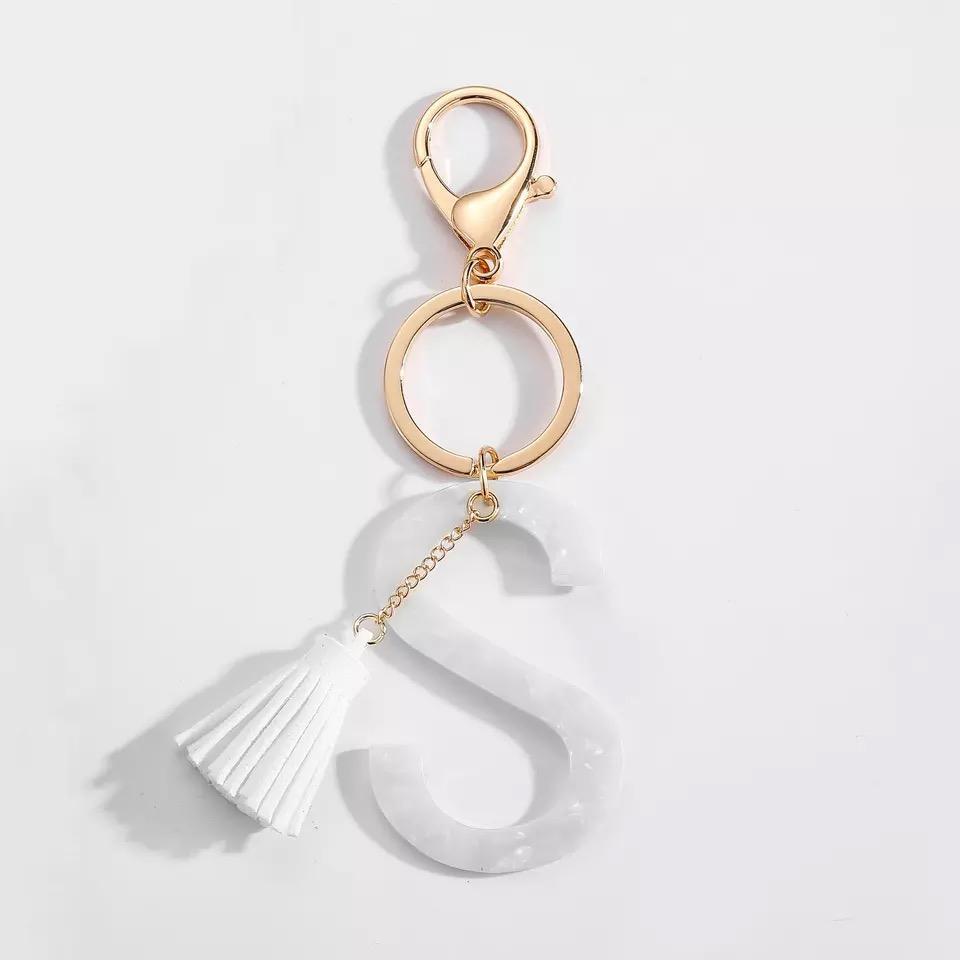 Stylish white key chain featuring a tassel and personalized initial, perfect for organizing keys.