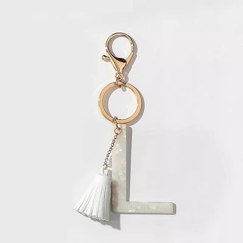 Stylish white key chain featuring a tassel and personalized initial, perfect for organizing keys.