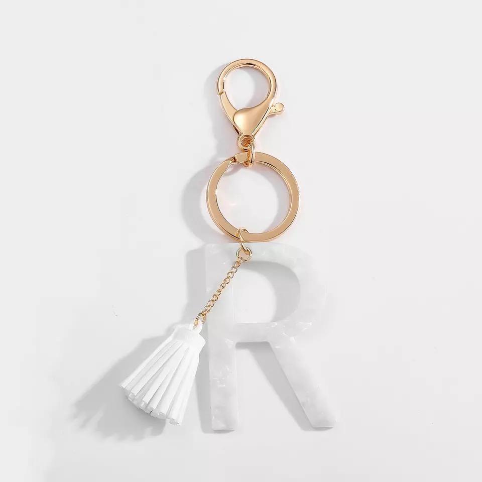 Stylish white key chain featuring a tassel and personalized initial, perfect for organizing keys.