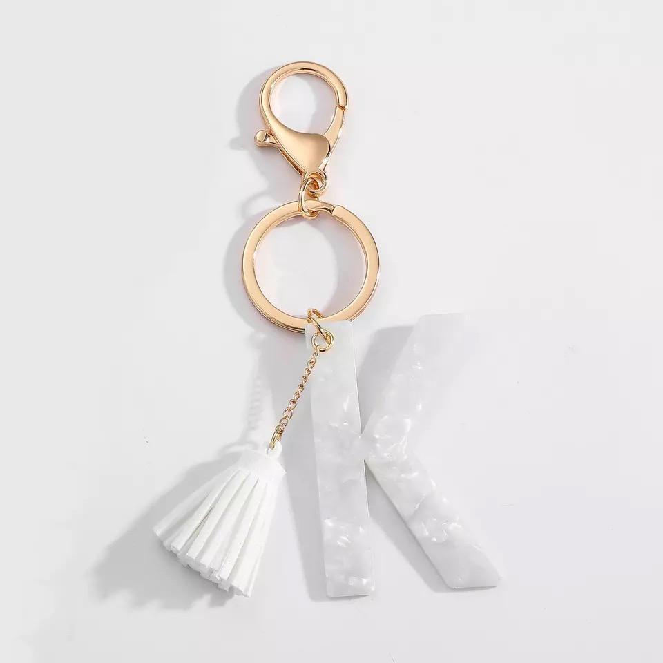 Stylish white key chain featuring a tassel and personalized initial, perfect for organizing keys.