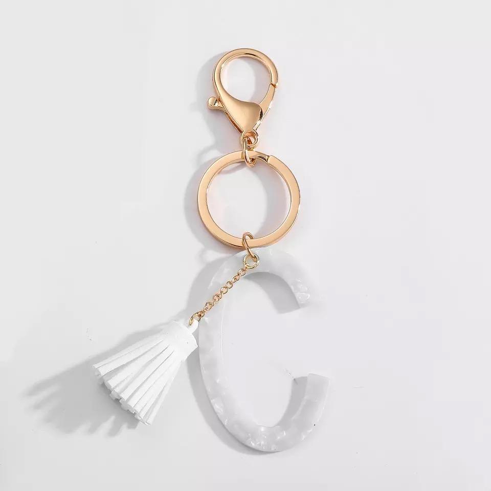 Stylish white key chain featuring a tassel and personalized initial, perfect for organizing keys.