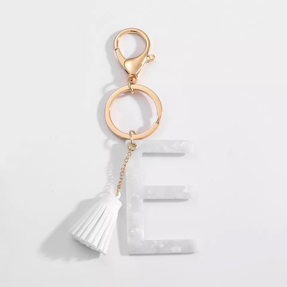 Stylish white key chain featuring a tassel and personalized initial, perfect for organizing keys.