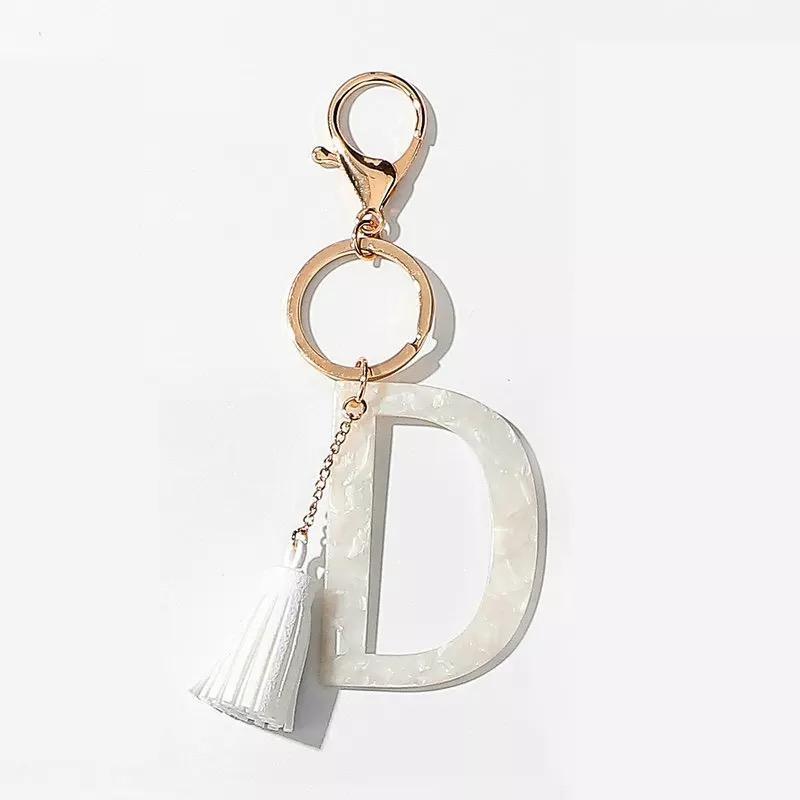 Stylish white key chain featuring a tassel and personalized initial, perfect for organizing keys.