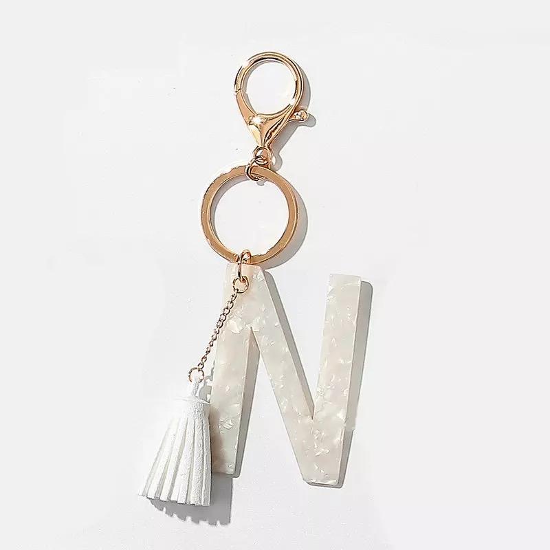 Stylish white key chain featuring a tassel and personalized initial, perfect for organizing keys.