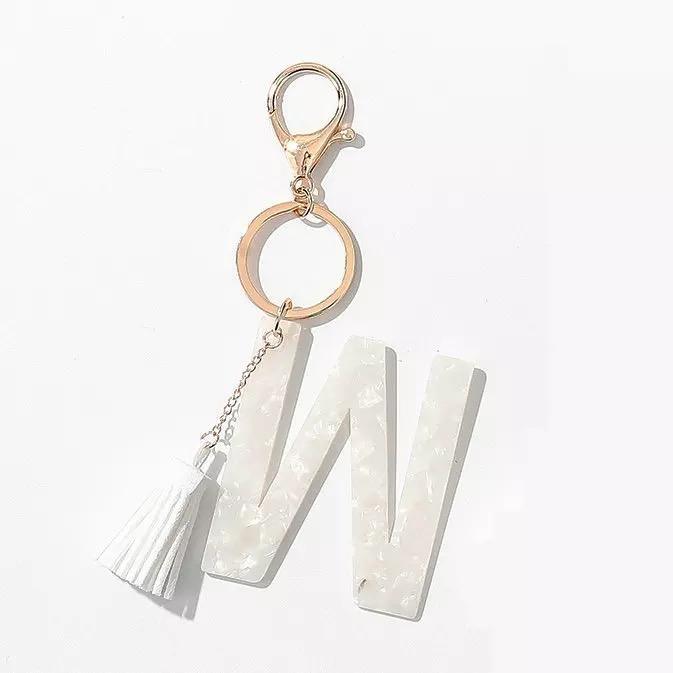 Stylish white key chain featuring a tassel and personalized initial, perfect for organizing keys.