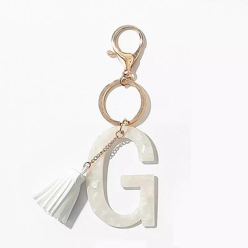 Stylish white key chain featuring a tassel and personalized initial, perfect for organizing keys.