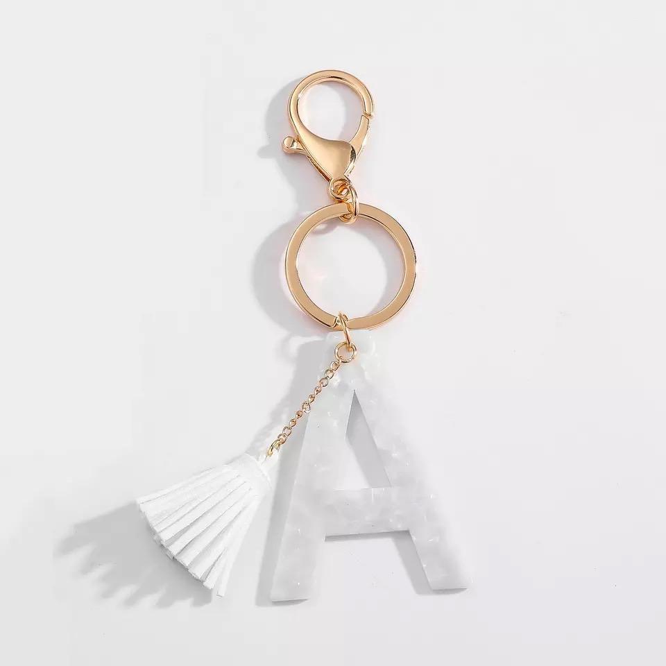 Stylish white key chain featuring a tassel and personalized initial, perfect for organizing keys.