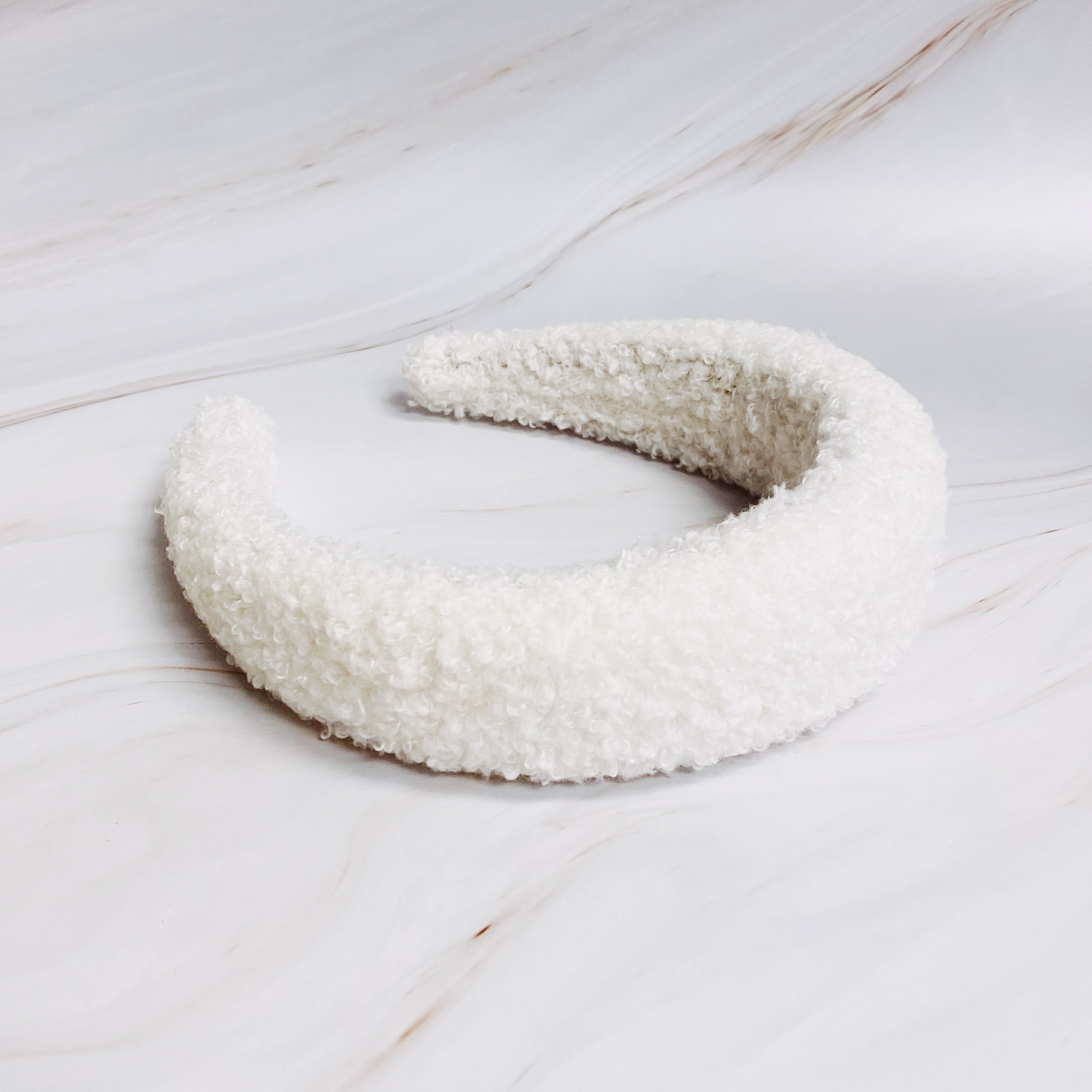 A stylish Teddy Cozy Headband made from soft, fuzzy materials, perfect for keeping hair in place while adding a cute touch to any outfit.