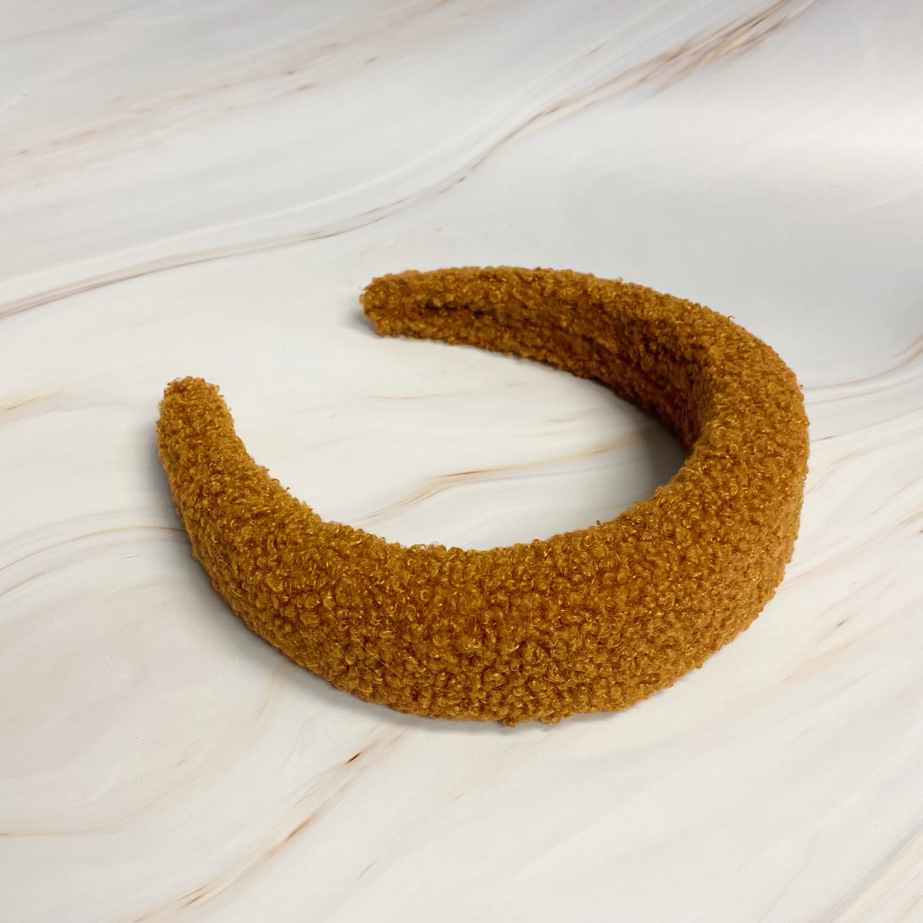 A stylish Teddy Cozy Headband made from soft, fuzzy materials, perfect for keeping hair in place while adding a cute touch to any outfit.