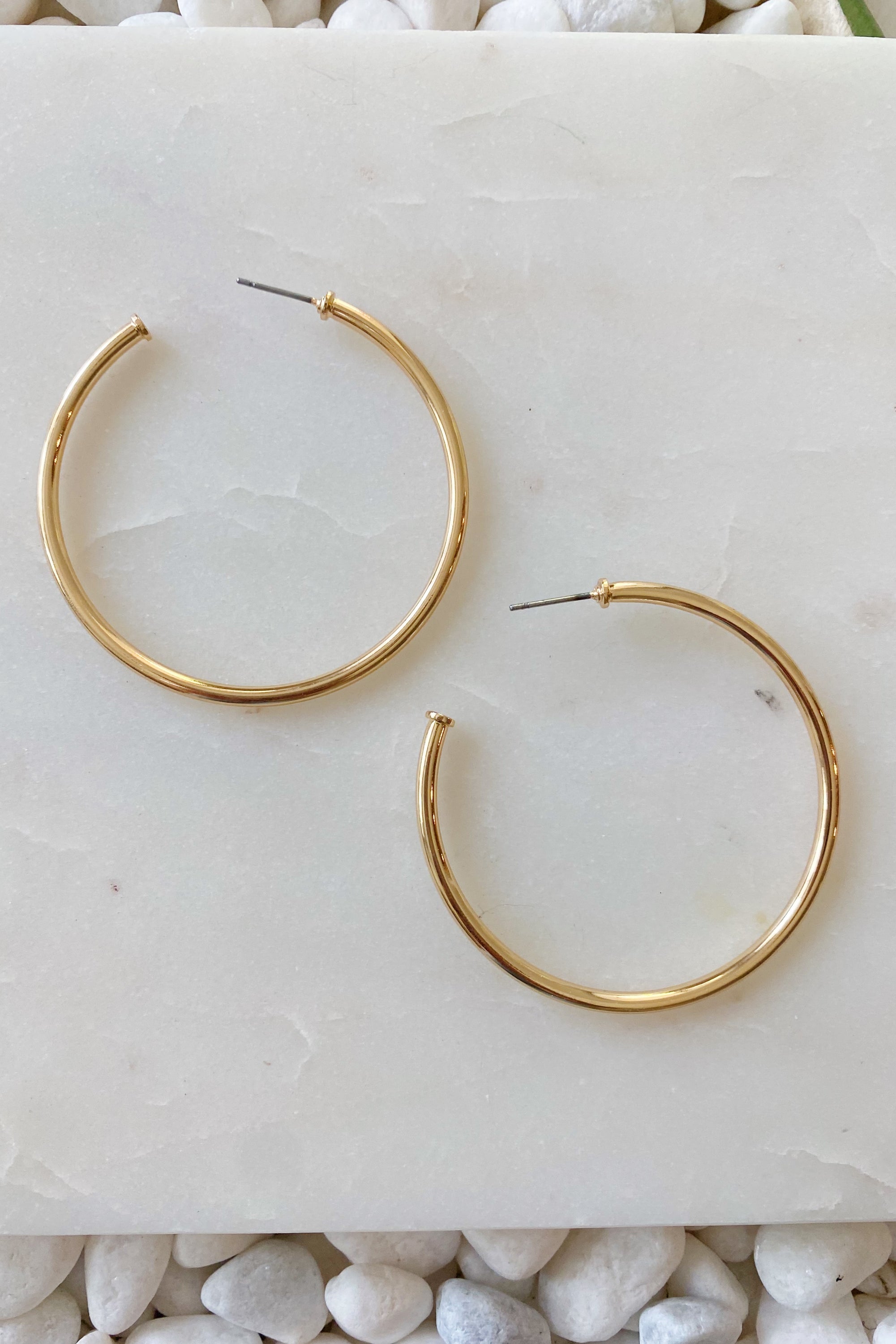 Shiny gold hoop earrings with a 2-inch diameter, lightweight and stylish, perfect for everyday wear.