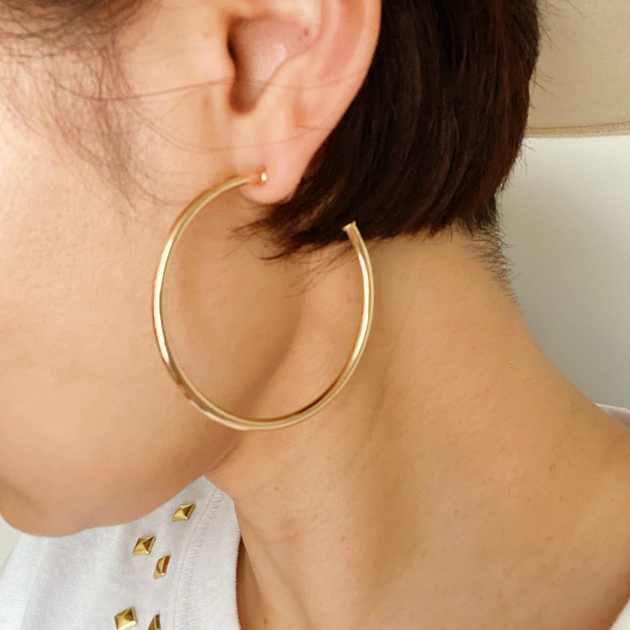 Shiny gold hoop earrings with a 2-inch diameter, lightweight and stylish, perfect for everyday wear.