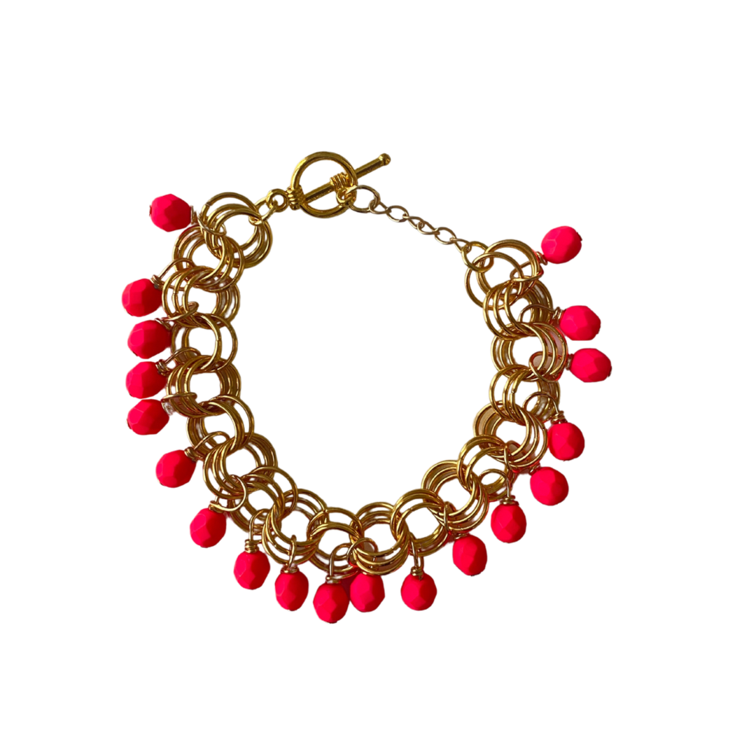 The Donna Bracelet in Neon Pink featuring Czech glass beads and a toggle clasp, elegantly displayed on a soft surface.