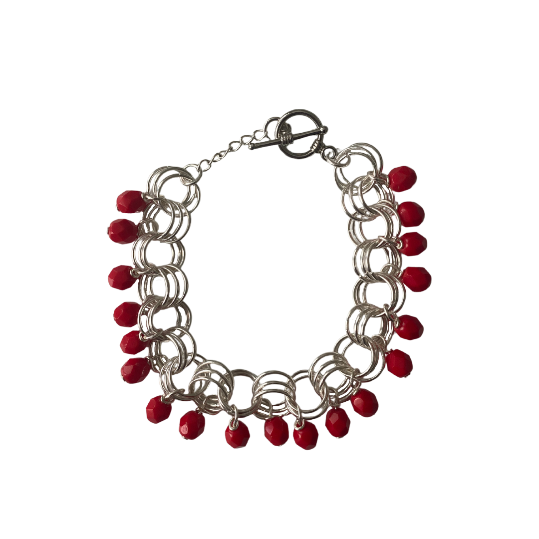 The Donna Bracelet in Opaque Red featuring Czech glass beads and premium metal links, elegantly displayed on a soft surface.