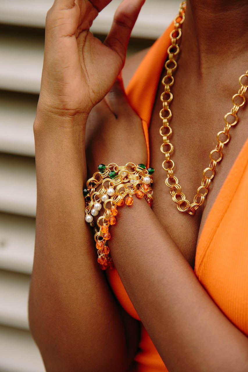 The Donna Bracelet in Orange featuring gold/silver-plated brass links and vibrant orange Czech fire-polished glass beads with a toggle clasp.