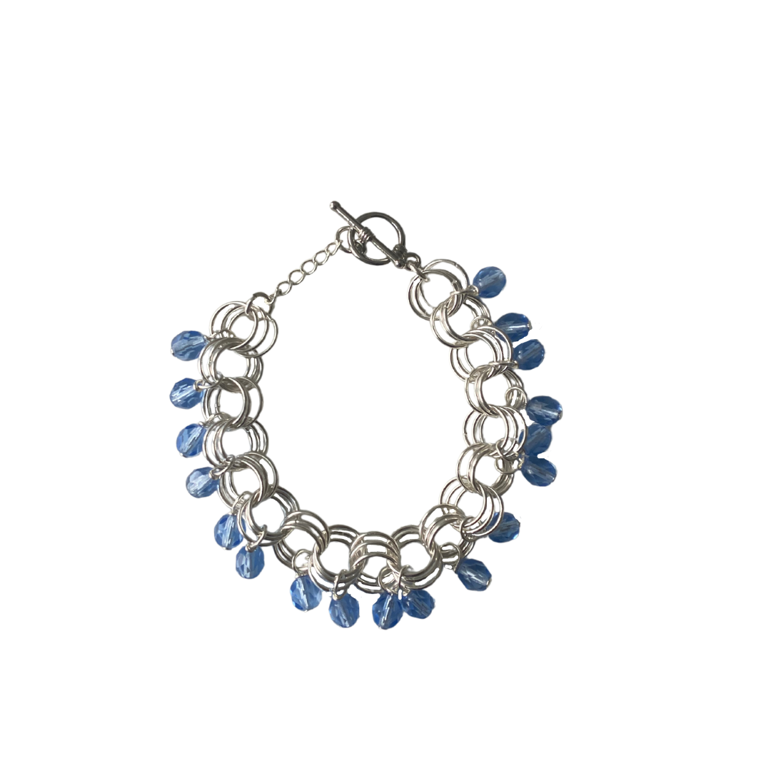 The Donna Bracelet in Sapphire Blue featuring Czech glass beads and a toggle clasp, elegantly displayed on a soft surface.