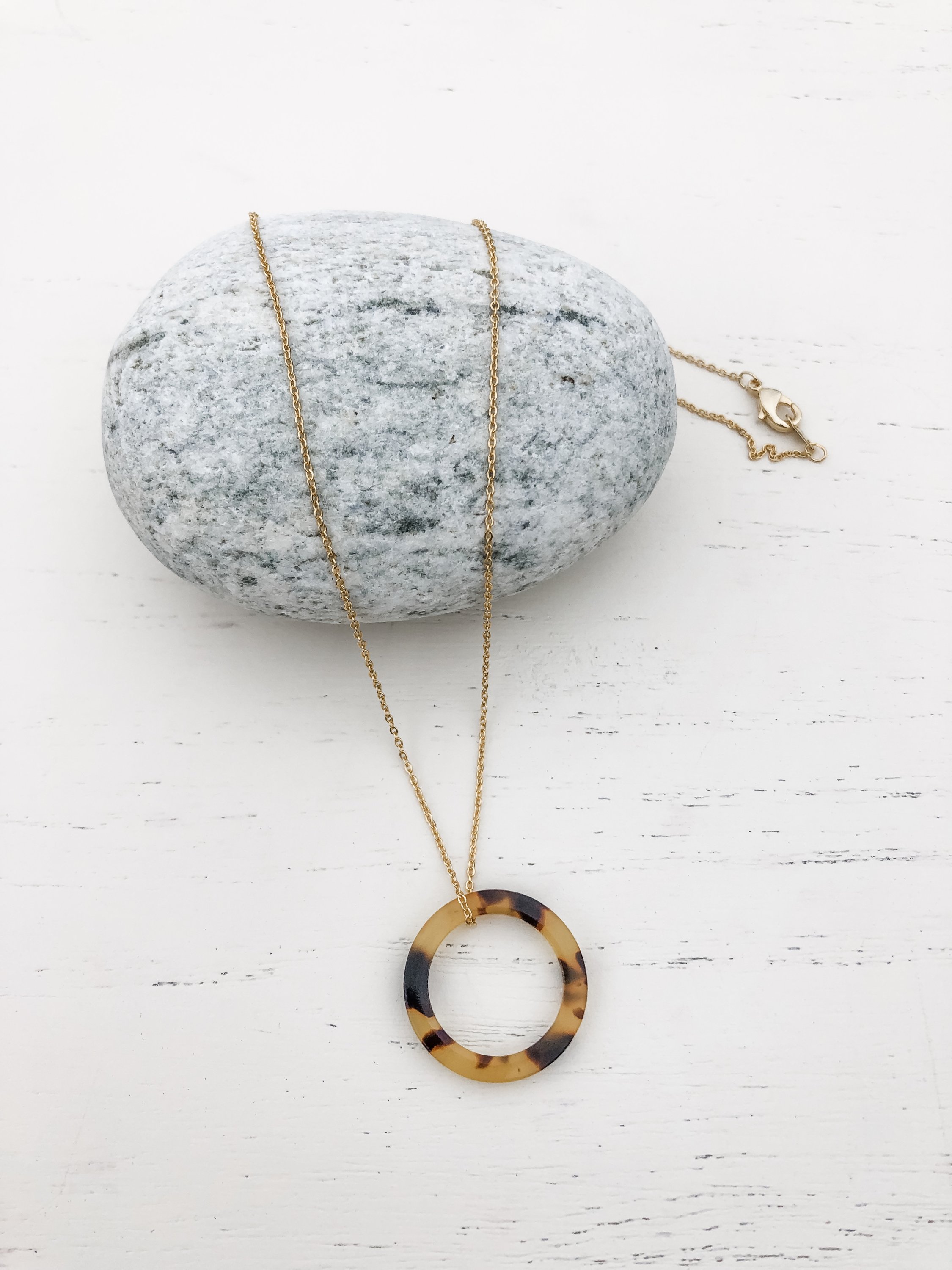 The Ellen Necklace in gold featuring a 17.5 inch chain and tortoise shell resin detail, elegantly displayed on a soft background.