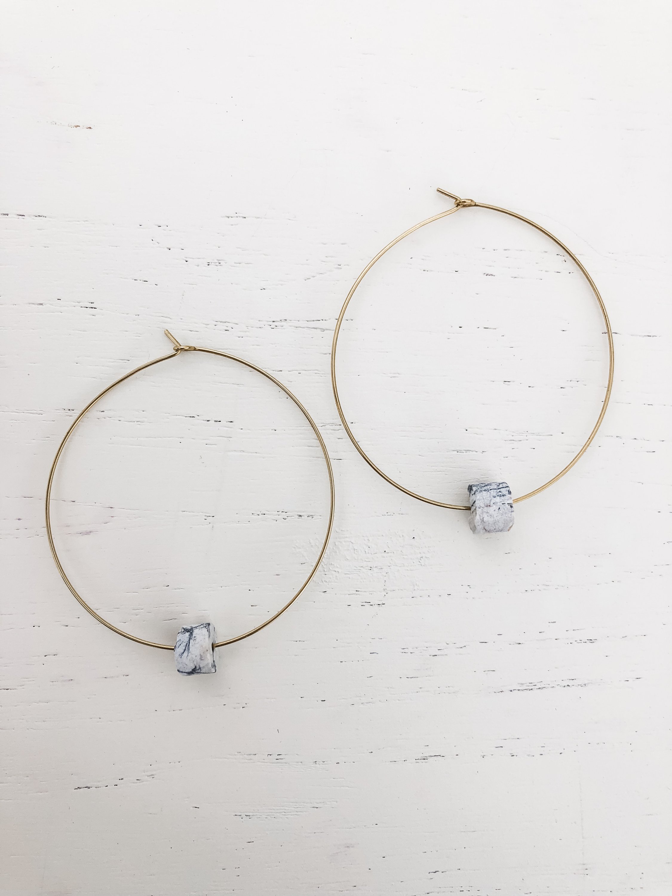 The Grey earrings featuring brass hoops and black water jasper detail, elegantly designed for a stylish look.