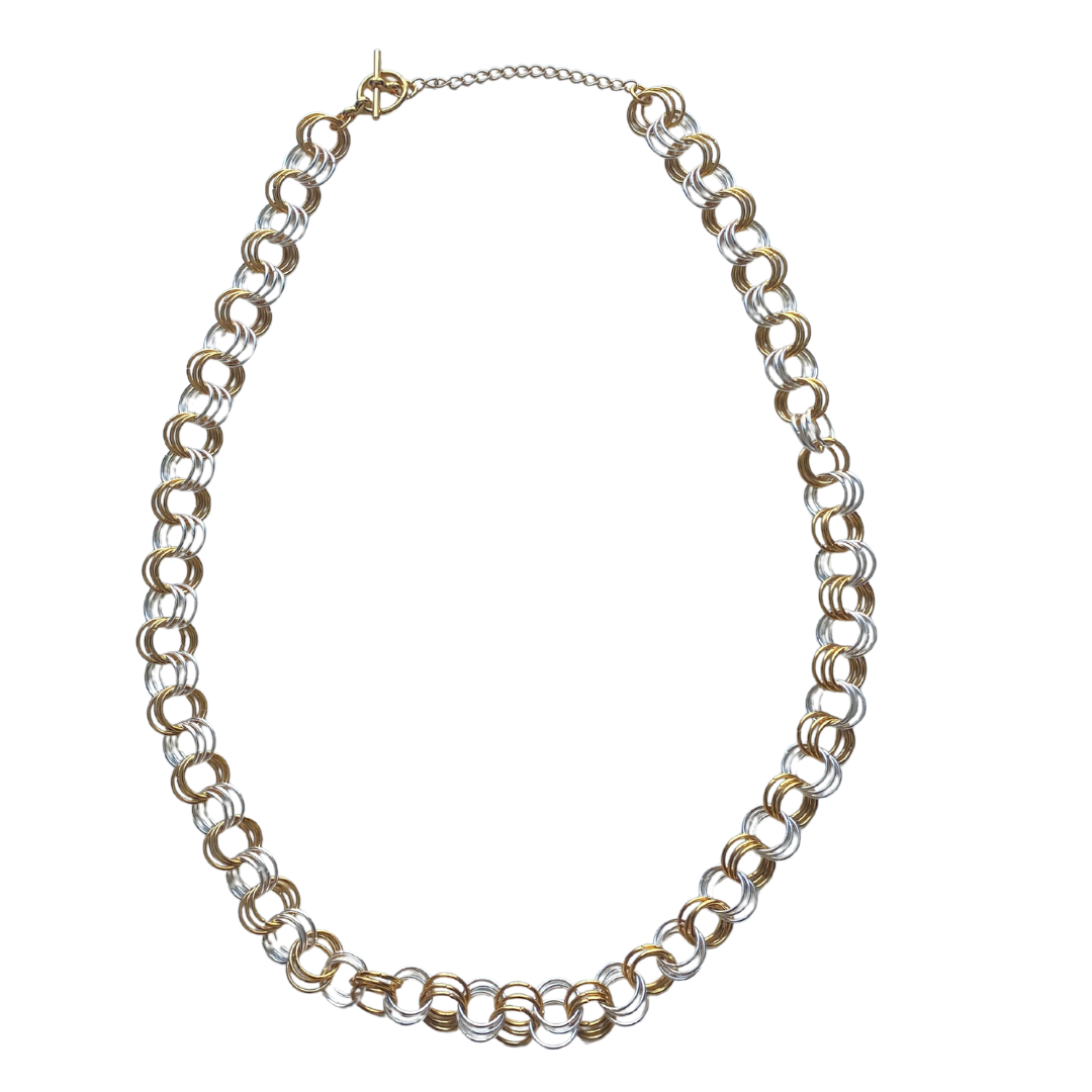 The Kyna Two-Tone Necklace featuring a handcrafted design with a toggle clasp, elegantly displayed on a soft background.