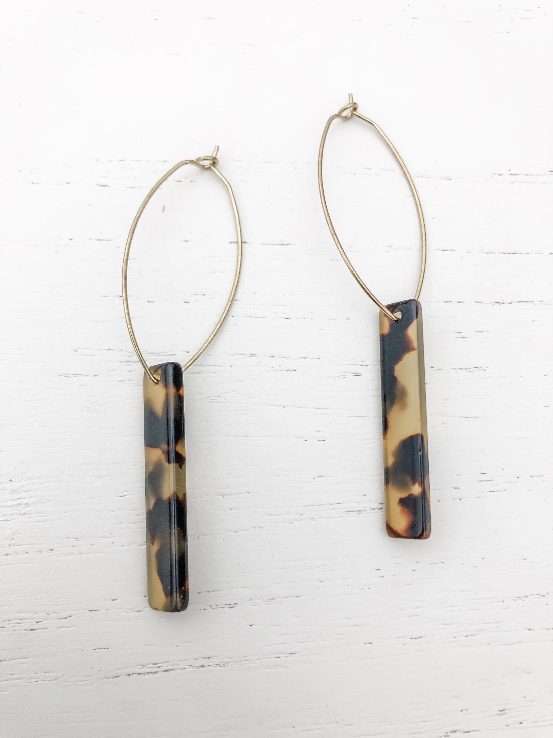 The Melissa Shortie Tortoise earrings featuring brass hoops and tortoise shell resin detail, elegantly displayed.