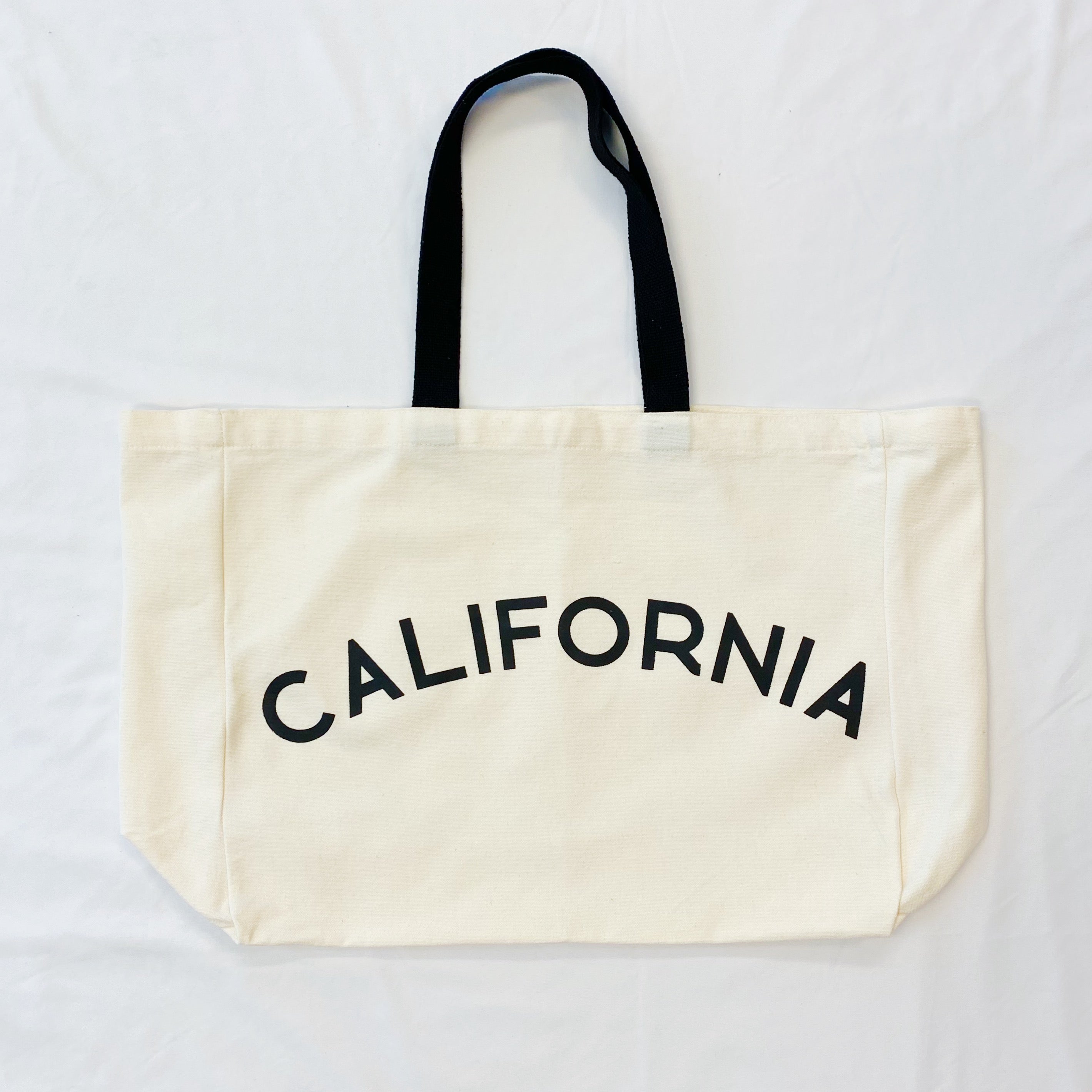 The State On My Mind Canvas Tote featuring a stylish state name print, spacious interior, and eco-friendly design.