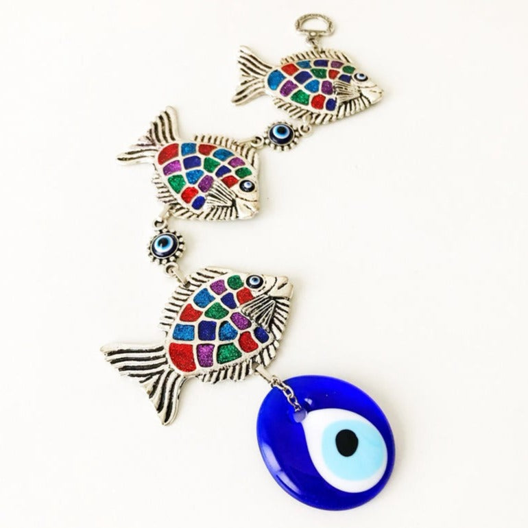 Three fish evil eye wall hanging featuring blue evil eye bead and metal fish charms, symbolizing protection and good luck.