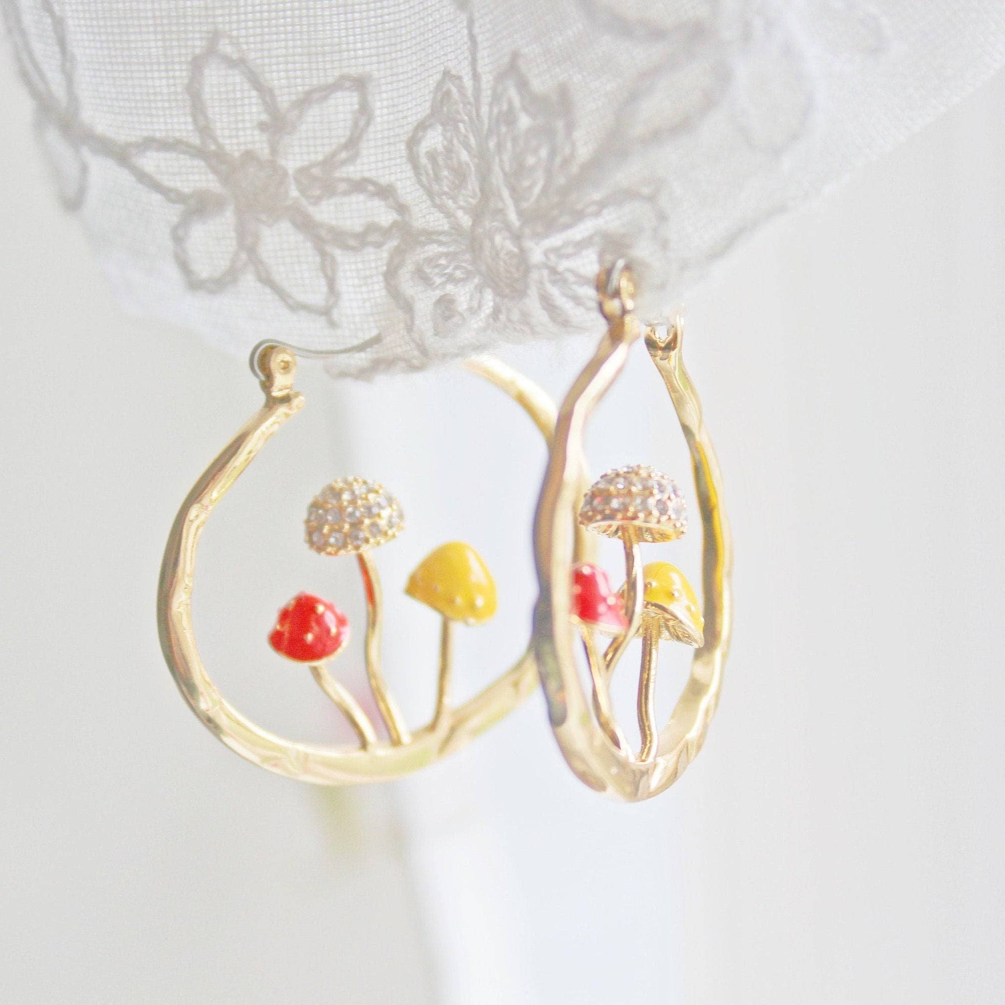 Three handmade gold hoop earrings featuring red fly agaric mushrooms, symbolizing good luck, with a gold plated bronze finish.