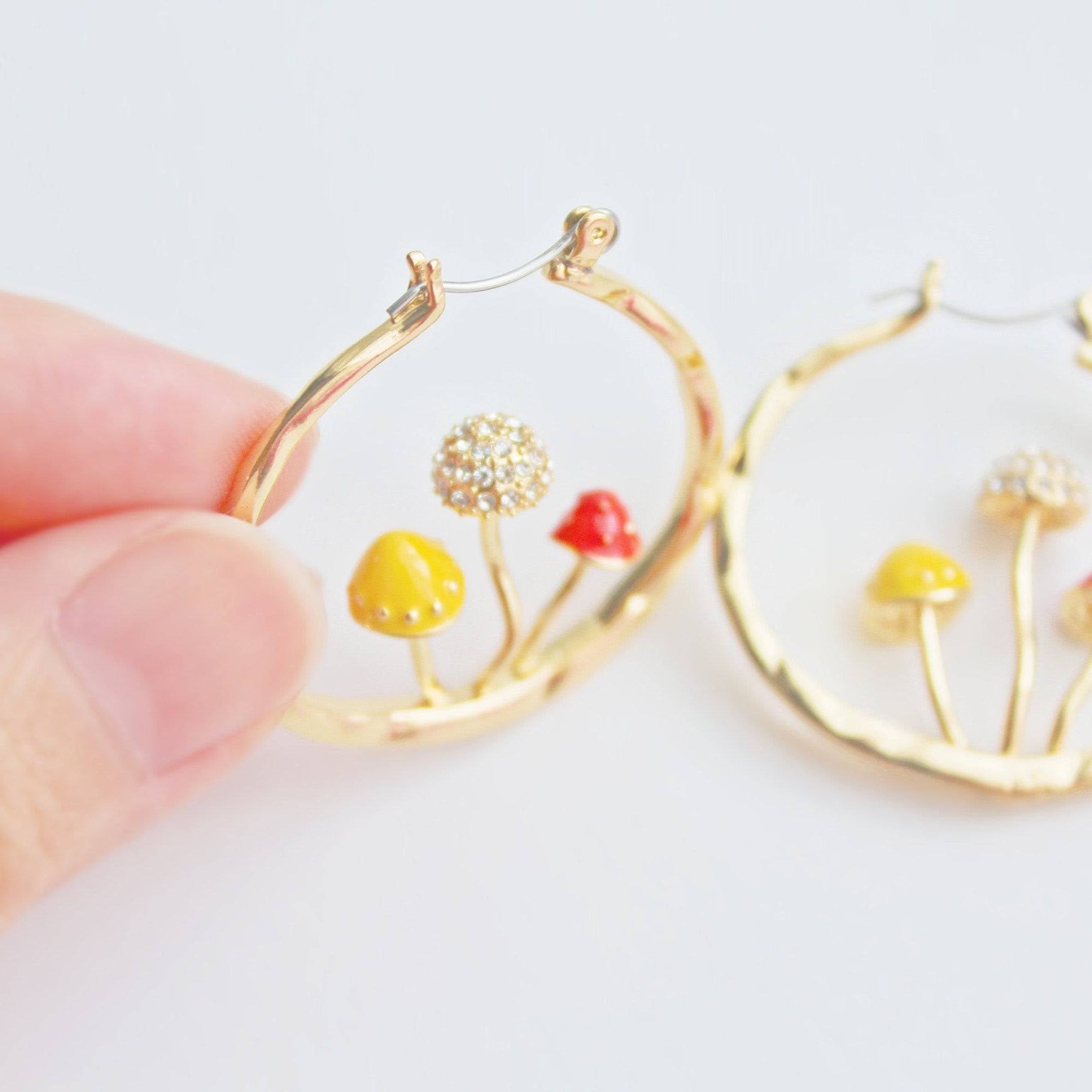 Three handmade gold hoop earrings featuring red fly agaric mushrooms, symbolizing good luck, with a gold plated bronze finish.