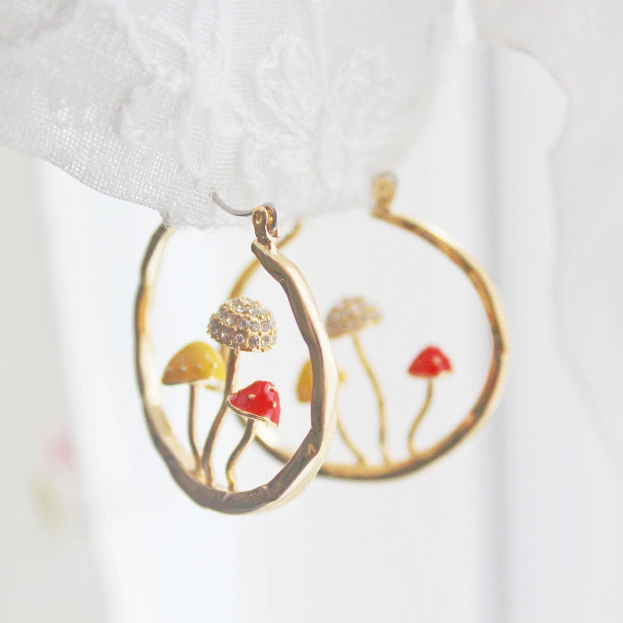 Three handmade gold hoop earrings featuring red fly agaric mushrooms, symbolizing good luck, with a gold plated bronze finish.