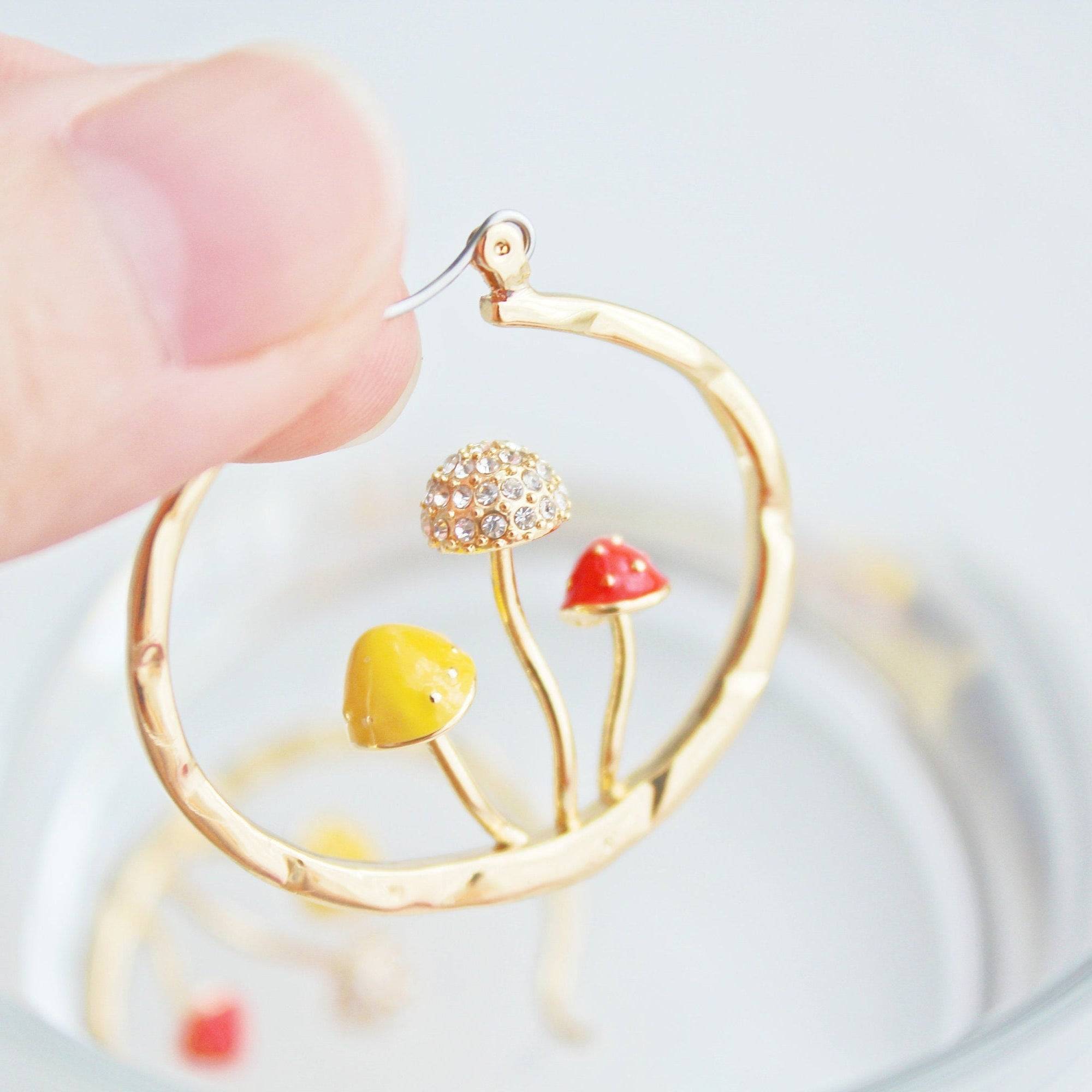 Three handmade gold hoop earrings featuring red fly agaric mushrooms, symbolizing good luck, with a gold plated bronze finish.