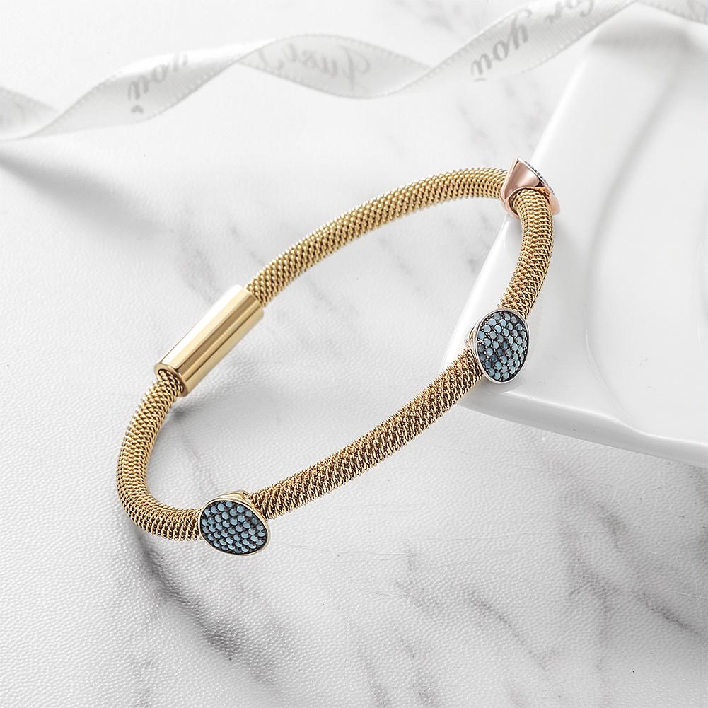 Three Stations Turquoise Cable Bangle featuring turquoise stones and gold accents on a stainless steel base.