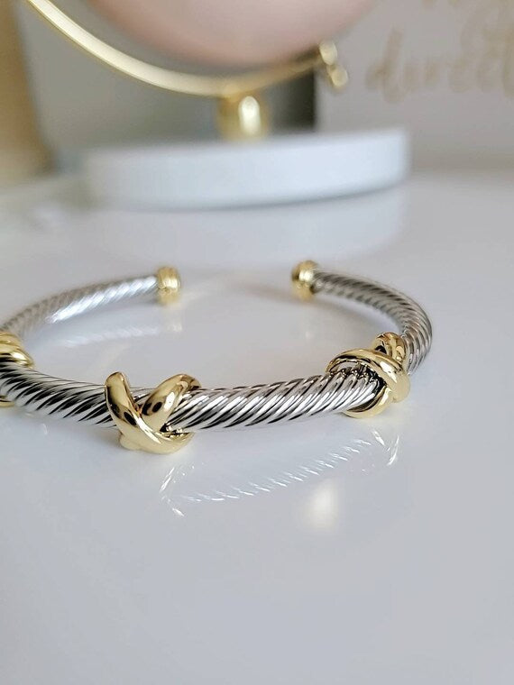 Three X Cable Cuff Bracelet featuring 18K gold filled details and stainless steel material, showcasing a unique three X pattern.